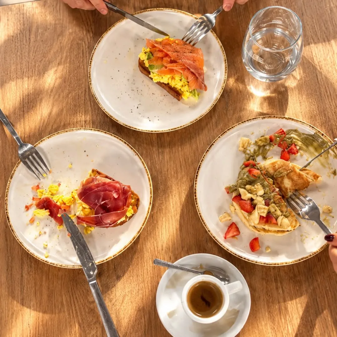 Mesa de desayuno con tostada de aguacate, huevos, tomate y café